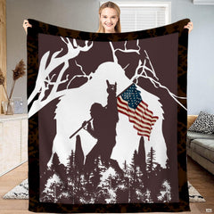 Patriotic Bigfoot blanket held open displaying the American flag Sasquatch graphic and camo border.