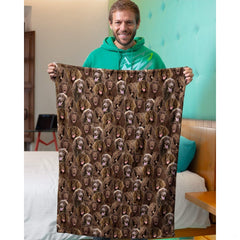 Model holding up a chocolate spaniel dog collage blanket in an indoor bedroom setting.
