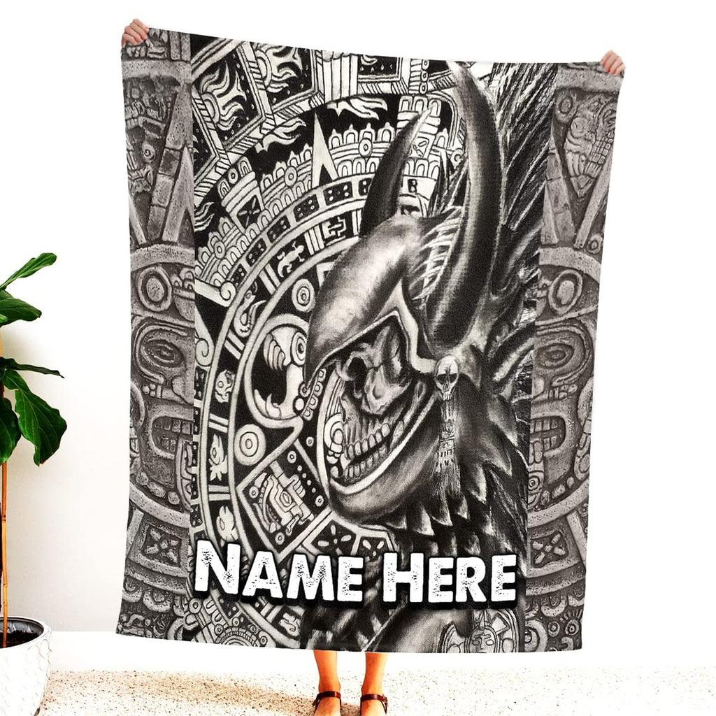 Person holding up black and white Aztec warrior skull blanket displaying horned helmet and stone glyphs