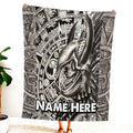 Person holding up black and white Aztec warrior skull blanket displaying horned helmet and stone glyphs