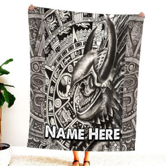 Person holding up black and white Aztec warrior skull blanket displaying horned helmet and stone glyphs