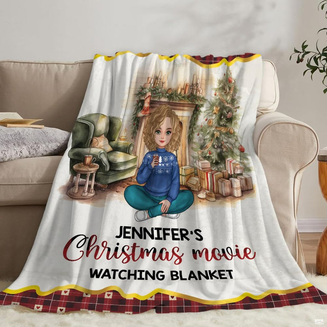 Living room staging of holiday throw blanket draped across a neutral sofa beside books.