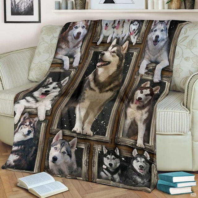 Alaskan Malamute throw blanket styled across a living room sofa near stacked books and a cup.