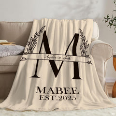 Detail shot of black typography and botanical leaf print on cream throw blanket