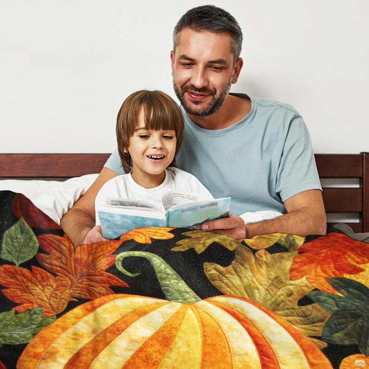Close-up perspective of quilted pumpkin and fall foliage on throw blanket