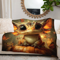 Folded baby dragon and pumpkin throw blanket displayed on wooden chair