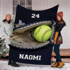 Two people standing outdoors in snow holding up the navy sports mitt and ball print.