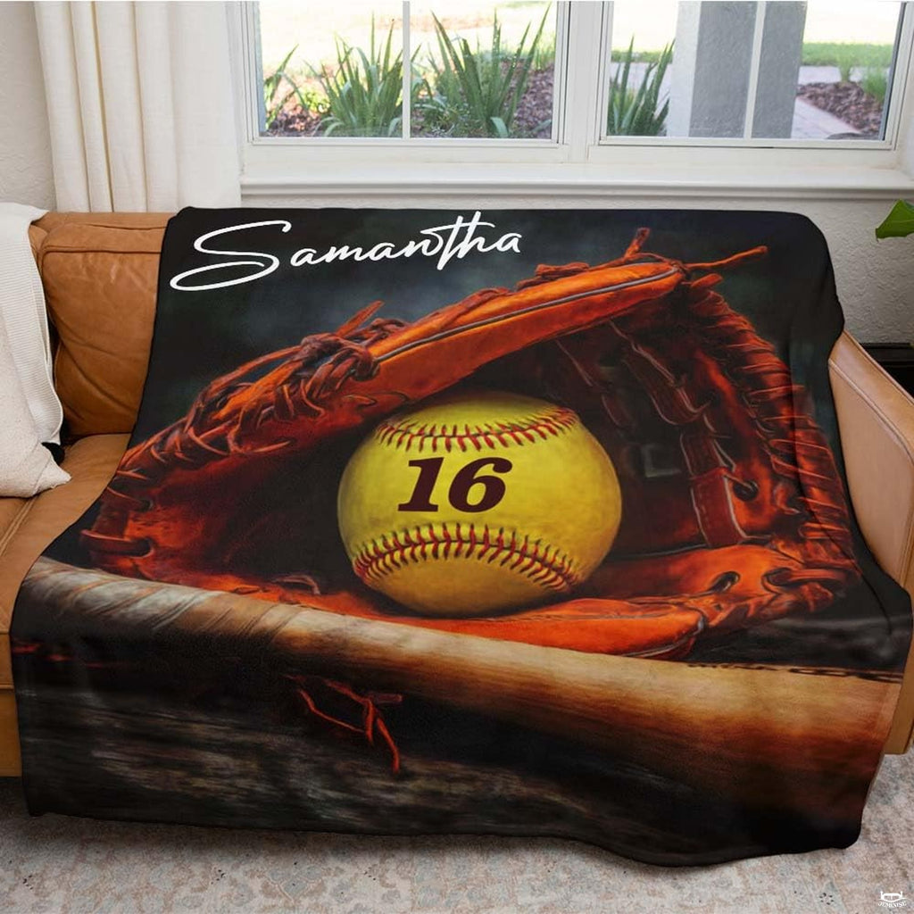 Close view of softball in mitt and wooden bat on graphic blanket