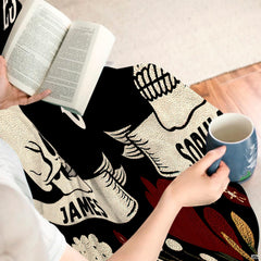 Overhead view showing gothic skull throw blanket folded with decorative pillows.