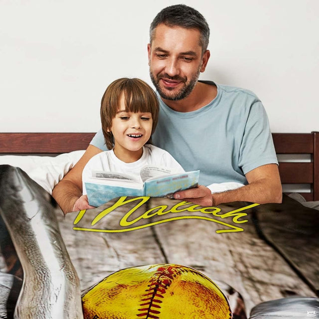 Father and son reading a book together in bed beside the displayed sports graphic piece.