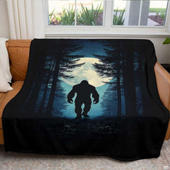 Nocturnal pine forest Bigfoot blanket draped over an indoor living room couch near a bright window.