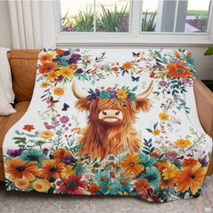 Folded botanical garden Highland cow throw blanket resting on wooden table displaying floral colors