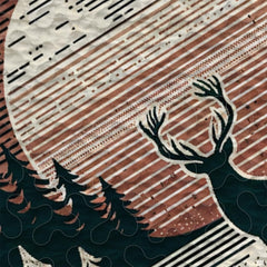 Close view of horned buck silhouette artwork surrounded by stylized botanical foliage and pines on bedding.