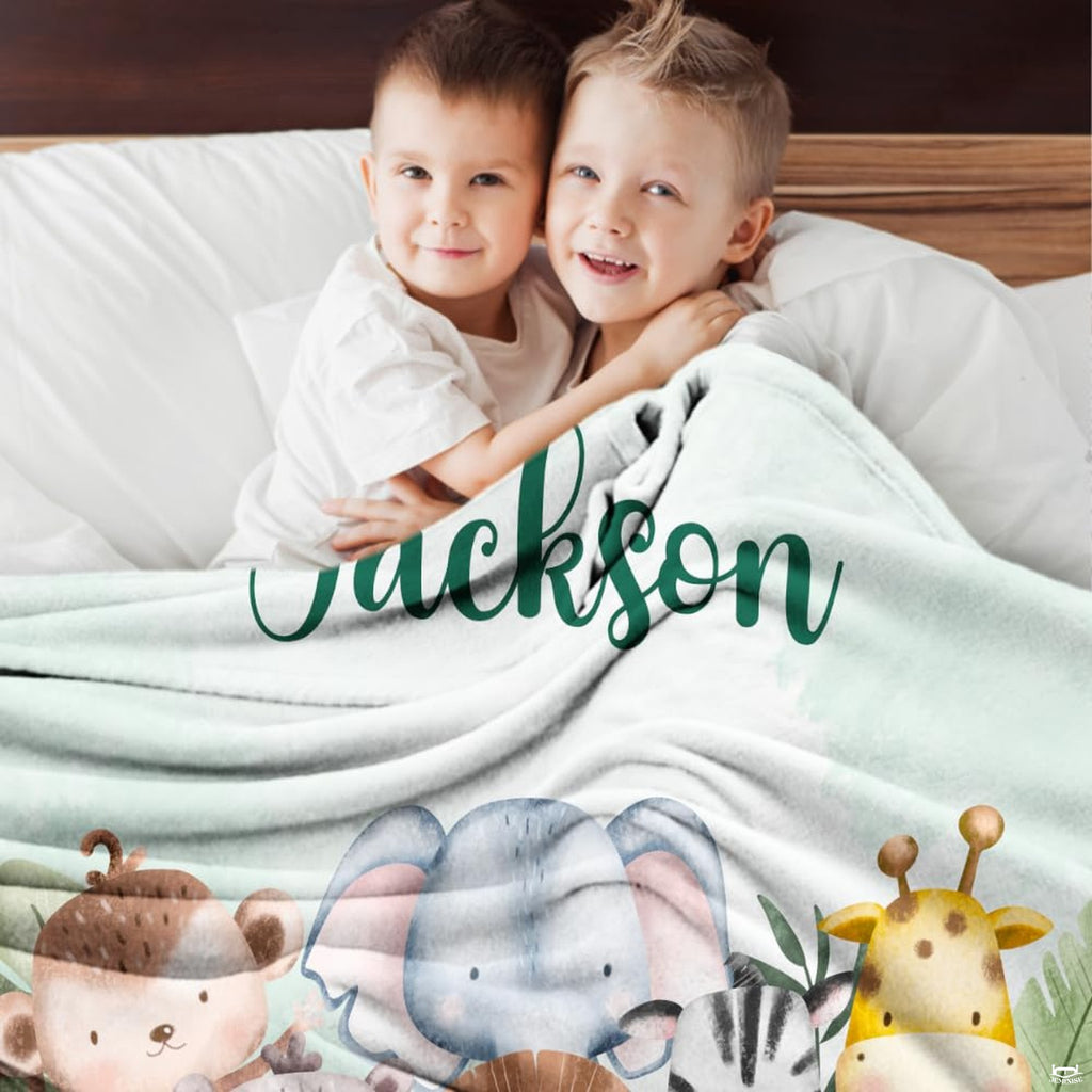 Two smiling children relaxing together indoors covered by watercolor safari animals blanket.