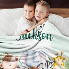 Two smiling children relaxing together indoors covered by watercolor safari animals blanket.