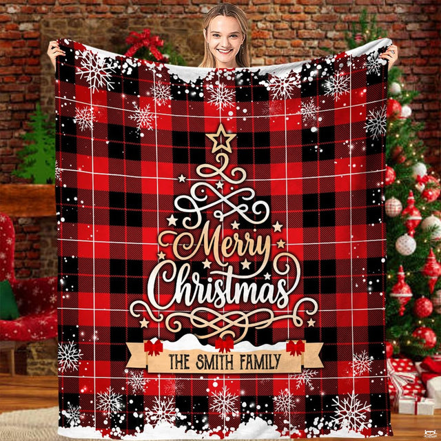 Buffalo plaid Christmas tree snowflake blanket held before tree