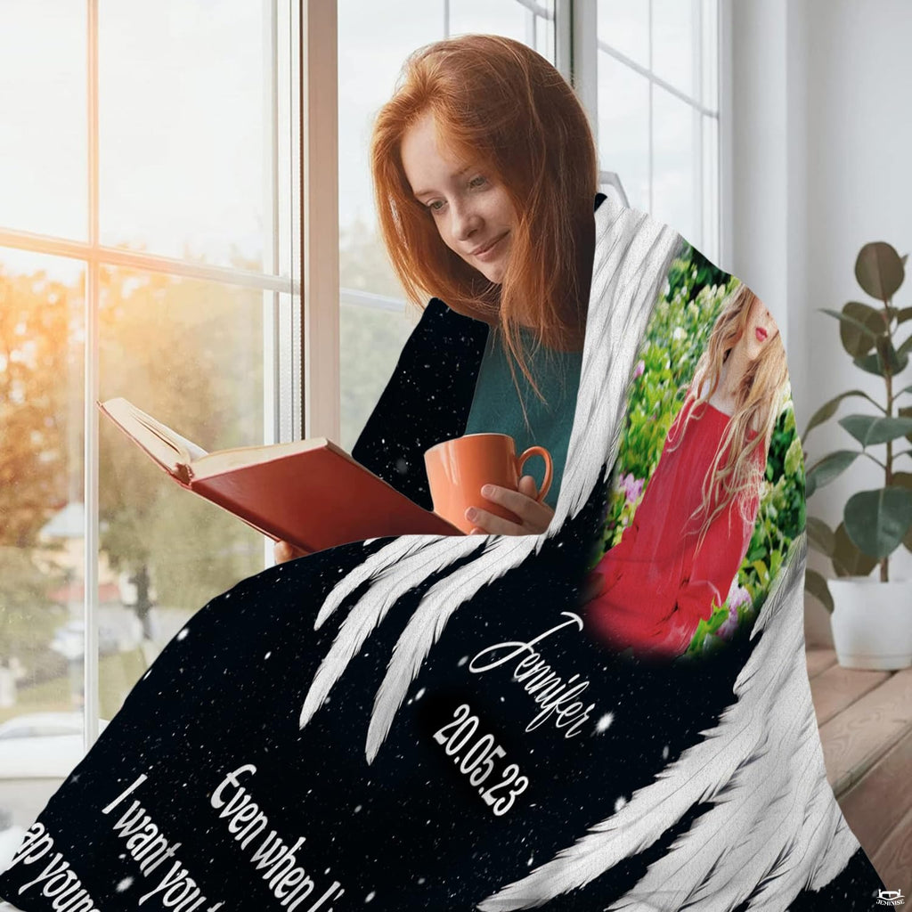 Woman seated beside a window wrapped in black celestial angel wings memorial throw blanket reading