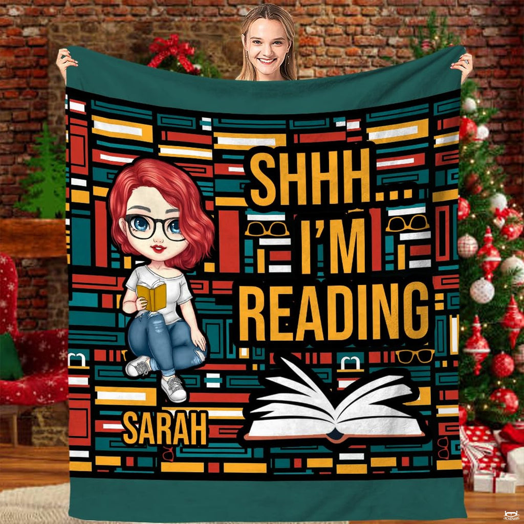 Front view of reader girl throw blanket showing geometric book spine mosaic and open volume graphic.