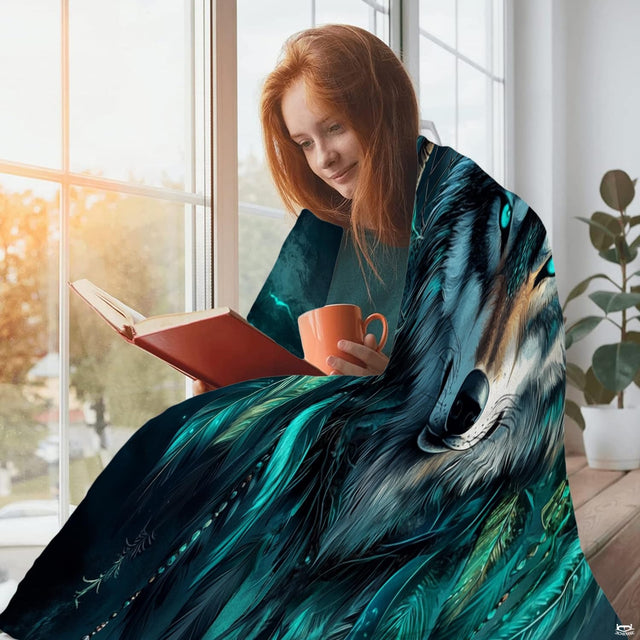Person sitting beside window holding mug with wolf dreamcatcher blanket.