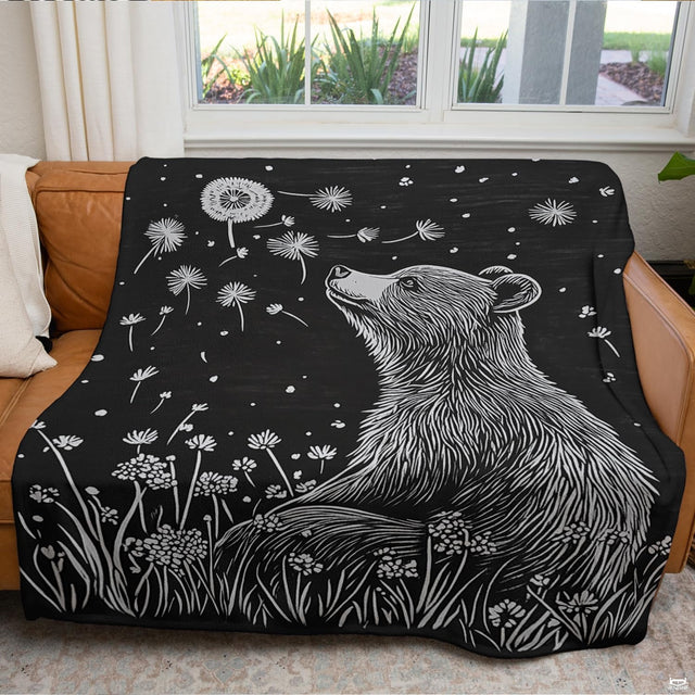Monochrome woodcut of gentle bear in wildflower meadow watching floating dandelion seeds, view 2.