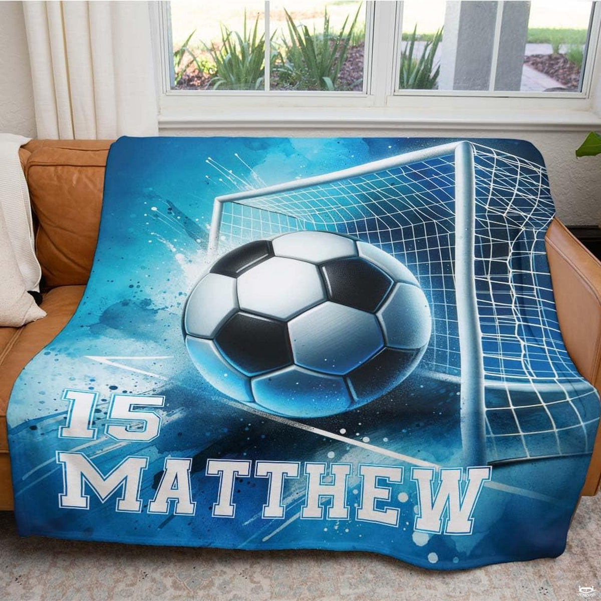 Living room display with the blue soccer goal design draped over a couch beside a window.