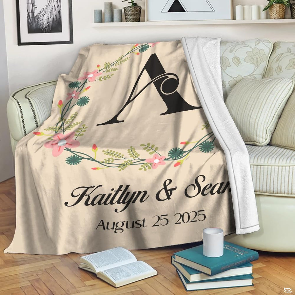 Folded wedding anniversary throw blanket displaying the central botanical wreath and initial lettering