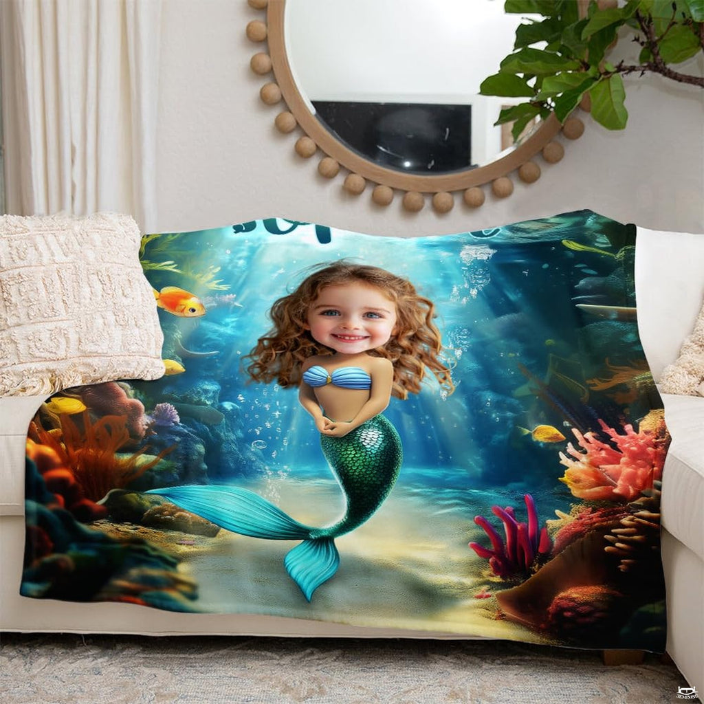 Oceanic mermaid graphic throw blanket folded across white living room couch beneath round mirror.
