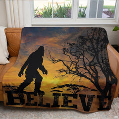Folded blanket showing rich amber sunset tones and Sasquatch figure outline.