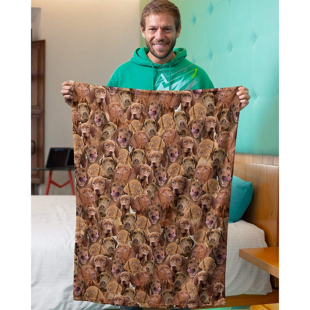 Model holding up a Vizsla dog collage blanket in an indoor bedroom setting.