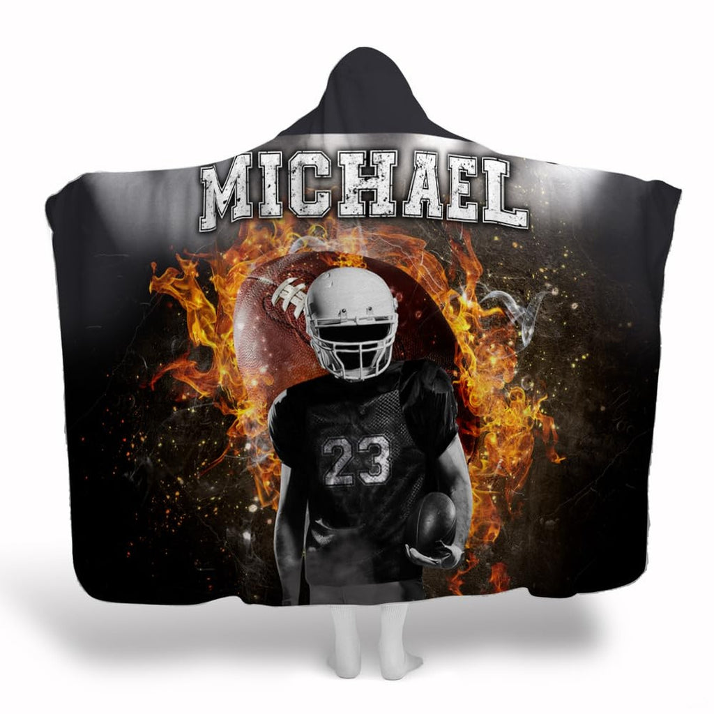 Football player standing before flaming football with stadium floodlights, view 1.