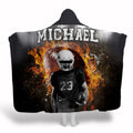 Football player standing before flaming football with stadium floodlights, view 1.