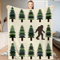 Bigfoot blanket held open showing geometric pine trees and walking Sasquatch silhouette on cream background.