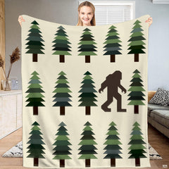 Bigfoot blanket held open showing geometric pine trees and walking Sasquatch silhouette on cream background.
