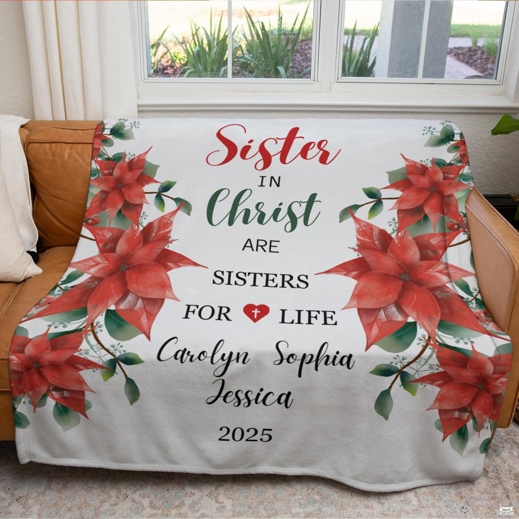 Red poinsettia holiday floral blanket draped over couch by window.