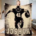 Football player silhouette throw blanket held upright showcasing charging athlete artwork and splatter textures.