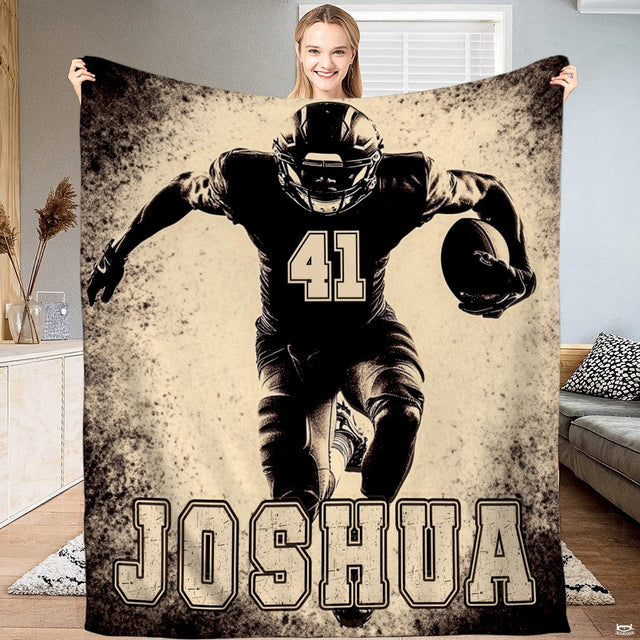 Football player silhouette throw blanket held upright showcasing charging athlete artwork and splatter textures.