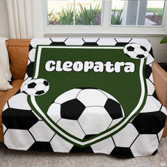 Close-up detail of forest green shield crest with bubbly white lettering and black and white soccer ball.