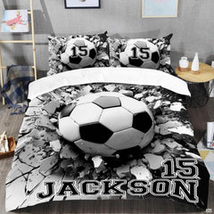 Close-up view of soccer bedding detailing textured soccer ball panels, concrete rubble fragments, and varsity lettering