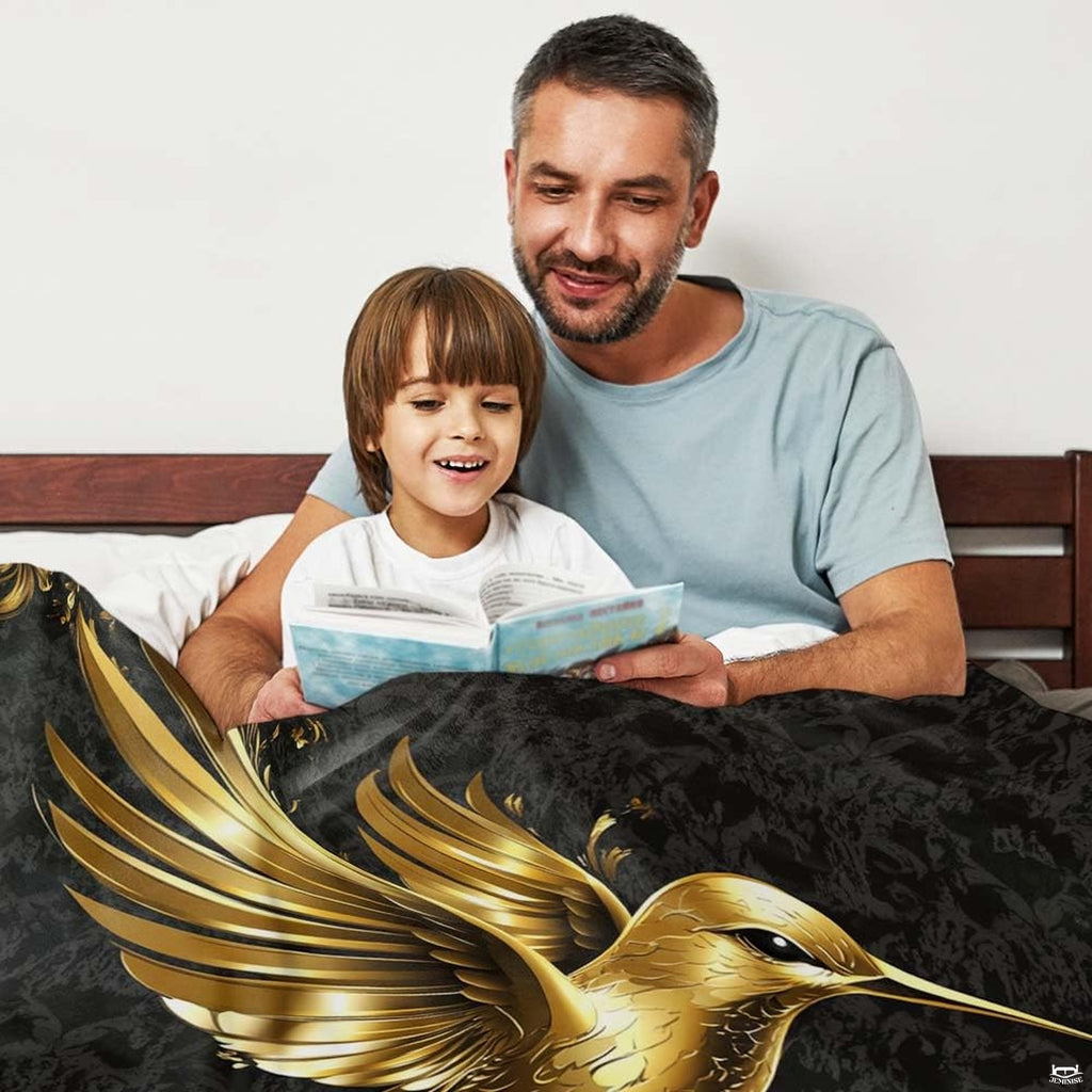 Luxury black and gold hummingbird throw blanket displayed across a bed.