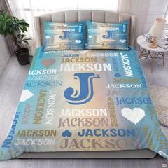Close-up view of bedding detailing bold initial outline, pixel heart motifs, and sand typography accents