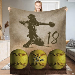 Woman holding up rectangular softball throw blanket showing complete player and ball graphics.