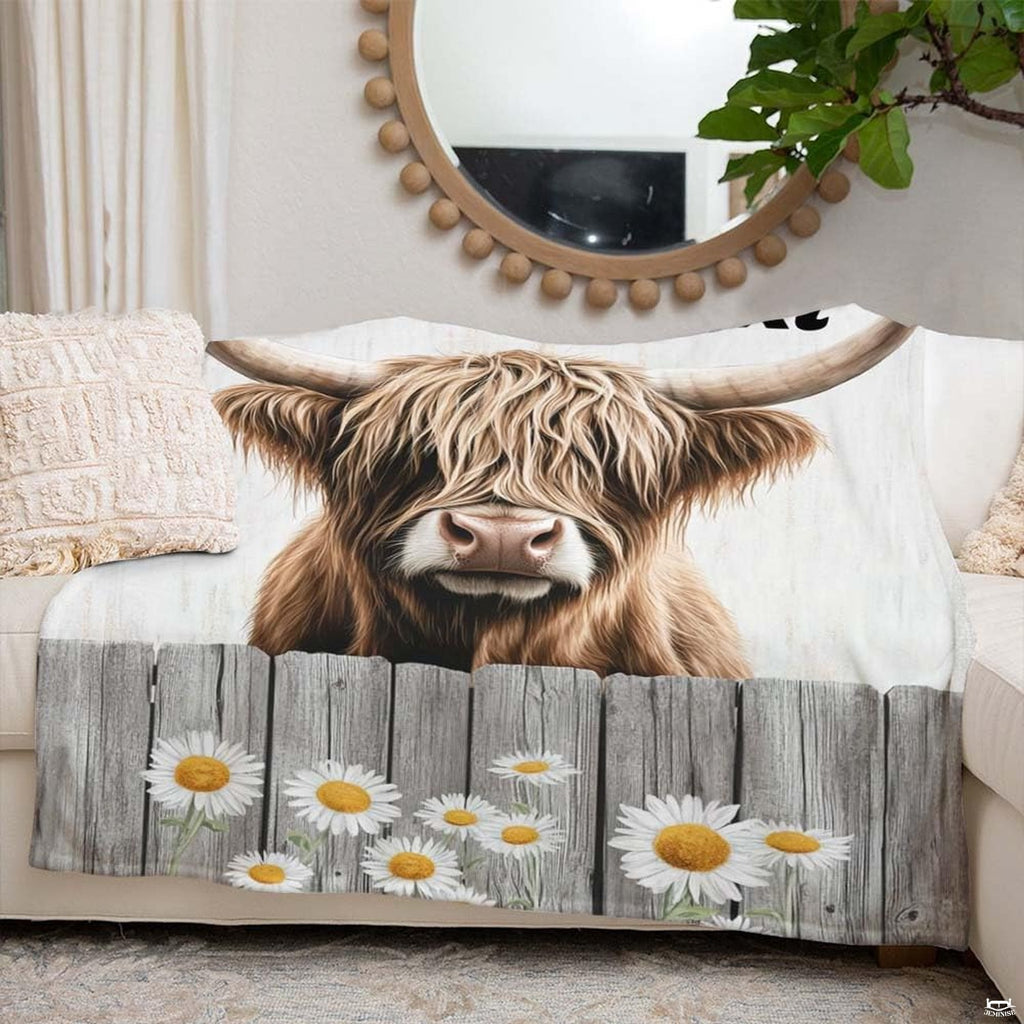 Bedroom styled with daisy fence Highland cow throw blanket displayed across rustic bedding