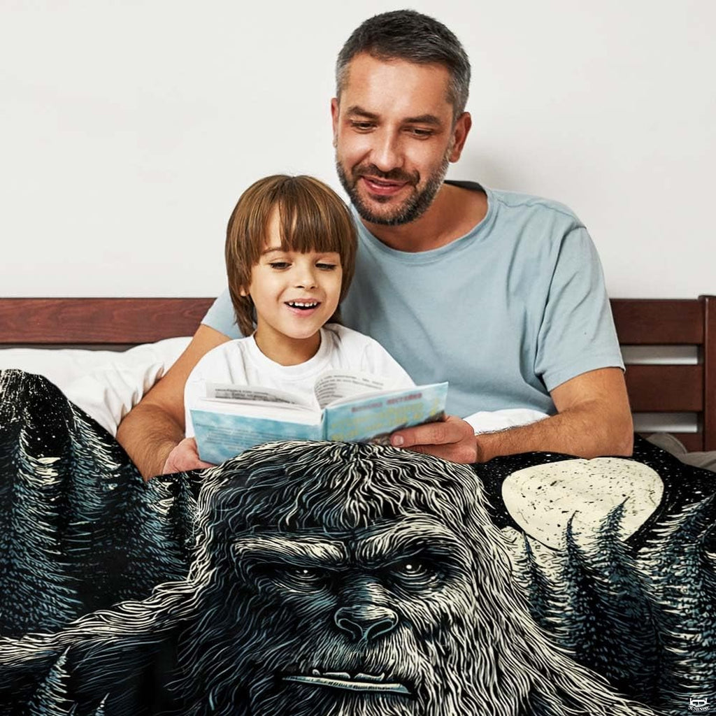 Close-up detail of the printed sasquatch facial artwork and glowing lunar texture on the throw blanket