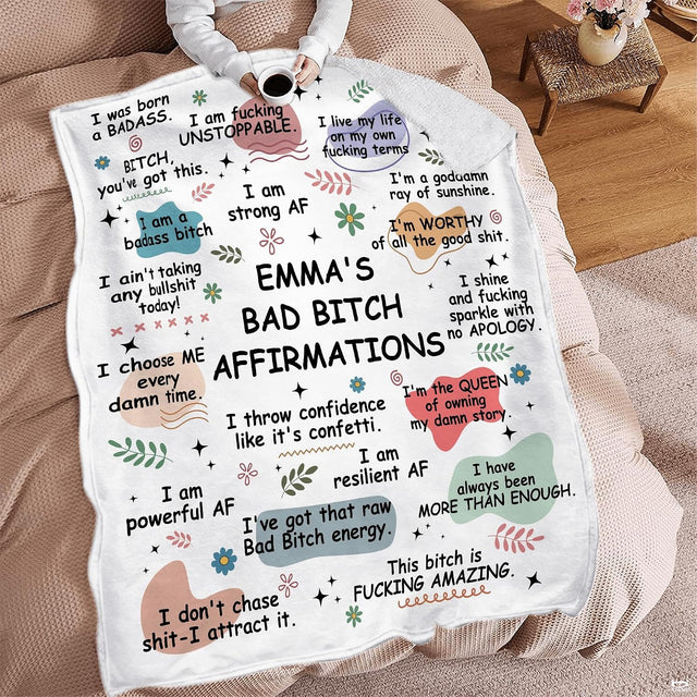 Woman holding open sassy affirmations throw blanket showing empowering quotes on white backdrop