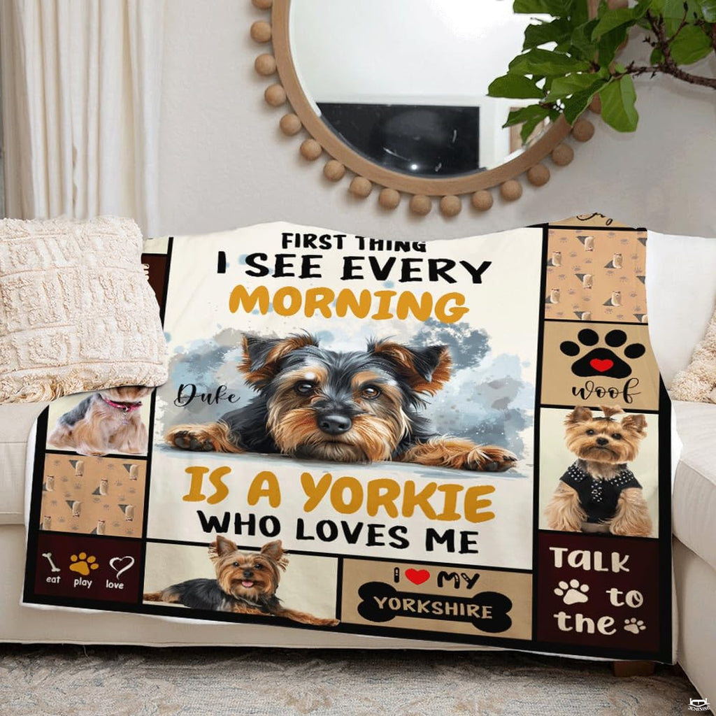 Dog collage blanket draped over living room couch beside round mirror.
