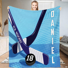 Full flat view of hockey sticks and puck throw blanket showing taped blades and vertical block lettering.