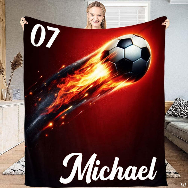 Person displaying the flaming soccer ball artwork with orange fire trail on deep crimson.