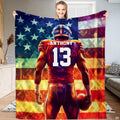 Football blanket held up displaying football player graphic against mosaic American flag