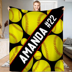 Front view of diagonal sash softball throw blanket displaying floating yellow softballs on black ground.
