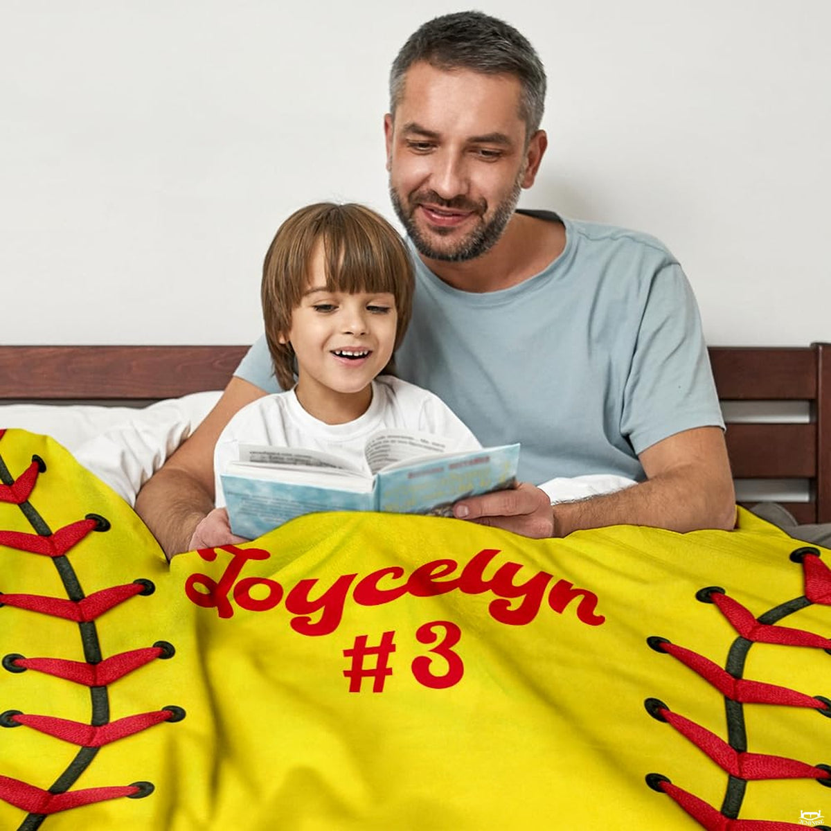 Adult and child reading in bed draped in vibrant yellow sports design.